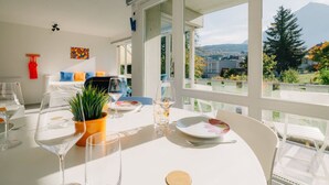 Un comedor con una mesa dispuesta para dos personas, ventanas amplias con vistas a la montaña y un ventilador de techo.
