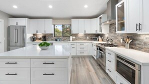 A modern kitchen with white cabinetry, stainless steel appliances, and a large island. - Scenic West Sedona Escape with Thunder Mtn Views (Sedona)