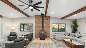 A modern living room with a fireplace, leather sofas, a coffee table, and a large window with a mountain view. - Scenic West Sedona Escape with Thunder Mtn Views (Sedona)