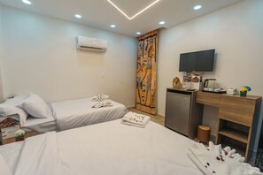 A hotel room with two beds, a desk with a television, a coffee machine, and an air conditioning unit. - Oriental Pyramids & GEM View (Giza)