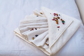 A stack of white towels with dried flower petals on a white bedspread. - Oriental Pyramids & GEM View (Giza)