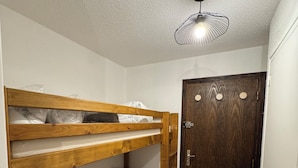 A small, narrow room with a bunk bed, a wooden door, and a ceiling light fixture. - Superb Cosy and Warm Studio Near Belle étoile chairlift (Les Deux Alpes)