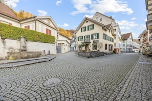 A cobblestone street with traditional European architecture, including a building with a balcony and a sign for a hotel. - ReMo I Old town idyll on Lake Walen #2 | Mountain (Weesen)
