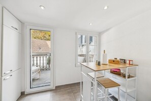A modern kitchen with white cabinetry, a wooden countertop, and a built-in white shelving unit.