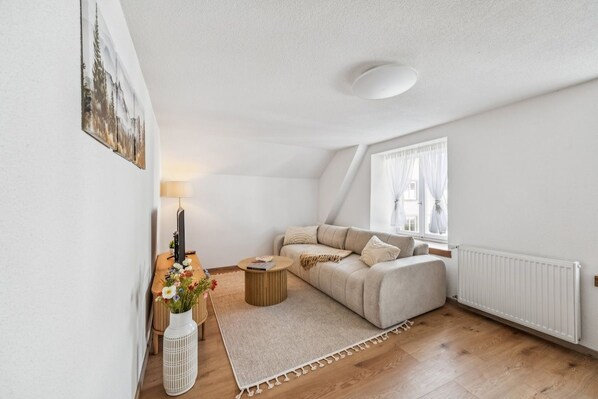 Un salon avec un canapé, une table basse, une lampe et une fenêtre avec des rideaux.