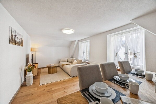 A modern living room with a dining area, a sofa set, and a fireplace.