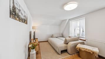 Une chambre confortable avec un lit, une table de chevet avec une lampe, une fenêtre avec des rideaux et un tableau accroché au mur.