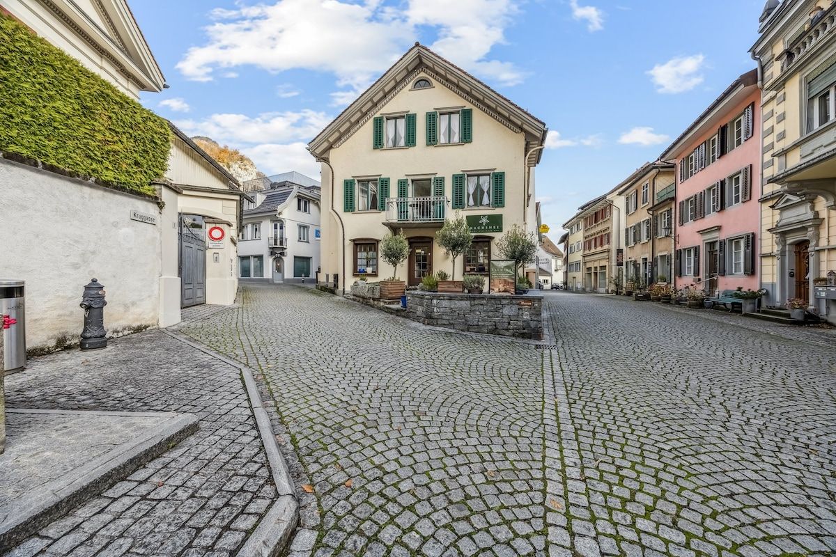 Een straat met kinderkopjes en historische gebouwen, met een zichtbare brandkraan en een bord waarop een restaurant wordt aangegeven.