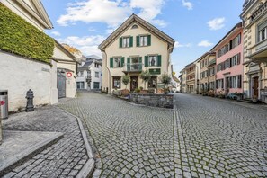 A cobblestone street with historic buildings, a visible fire hydrant, and a sign indicating a restaurant.