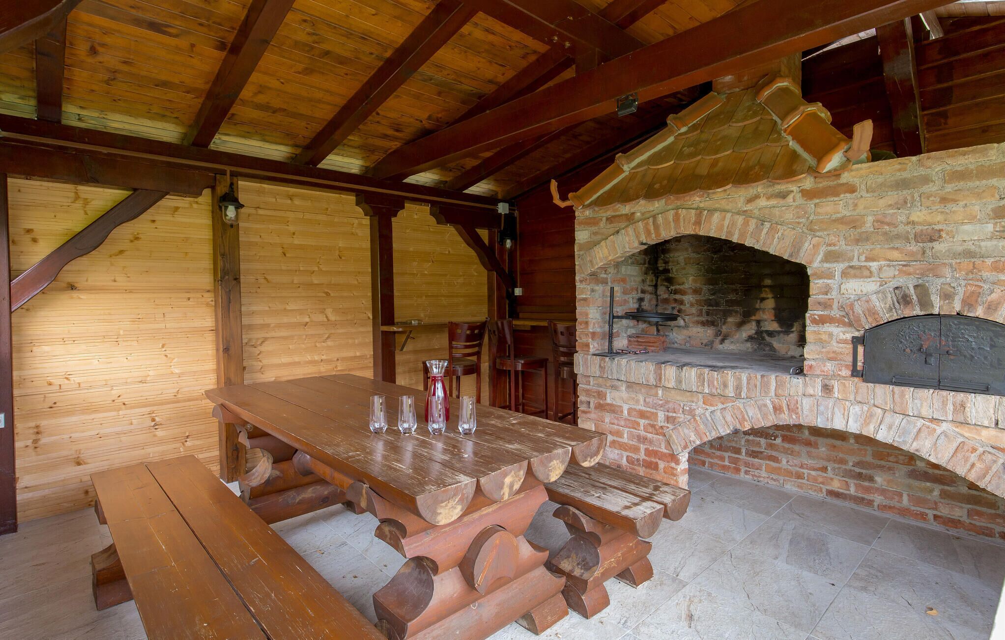 Zona pranzo rustica in legno con camino in mattoni e pavimento in pietra.