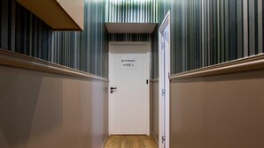 A hallway with wooden flooring, striped wall panels, and a door labeled "Home". - Authentic Apartment in Paris (Paris)