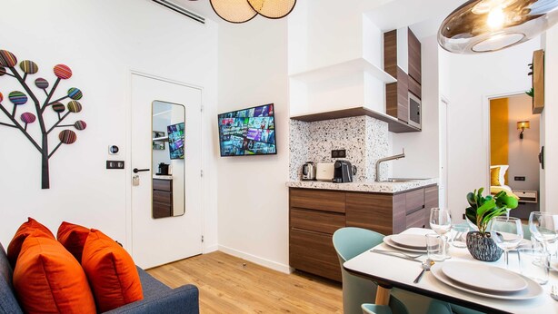 A modern kitchen with a built-in stove, a dining table set for four, and a large mirror above the counter. - Authentic Apartment in Paris (Paris)