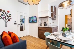 A modern kitchen with a built-in stove, a dining table set for four, and a large mirror above the counter. - Authentic Apartment in Paris (Paris)