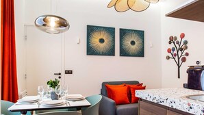 A modern kitchen with a wooden countertop, a dining area with chairs, and a hanging light fixture. - Authentic Apartment in Paris (Paris)