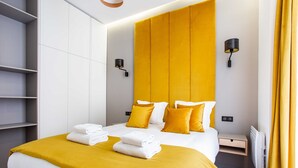 A modern hotel room with a large bed, a bedside table, a built-in shelf, and a wall-mounted lamp. - Authentic Apartment in Paris (Paris)