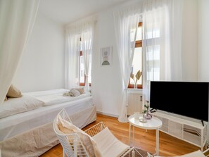 Een kamer met twee bedden, een televisie en een klein tafeltje met een vaas.
