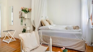A bedroom with a bed, a chair, a shelf with plants, and a mirror. - Arcadio Home - Junior Suite (Graz)