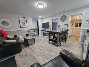 A modern living room with a leather sofa, a coffee table, and a dining area with a kitchen in the background.