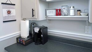 A kitchen with white cabinets, a coffee station, and a countertop with a coffee maker and paper towels. - Tiny Home| Full Kitchen | Sleeps 4 + Work Desk. Relax, explore Acadian Peninsula (Allardville Parish)