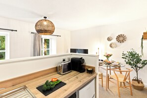 A modern kitchen with a wooden countertop, a toaster, a coffee maker, and a dining area with a table and chairs.