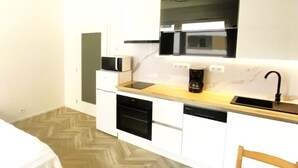 A compact kitchen with a microwave, oven, and coffee maker on a wooden countertop. - Apartment 10 min walk to center (Jihomoravský kraj)