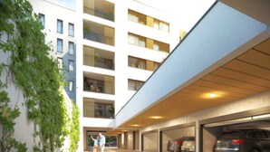 A modern building with multiple floors, a covered parking area, and a visible car. - Apartment 10 min walk to center (Jihomoravský kraj)