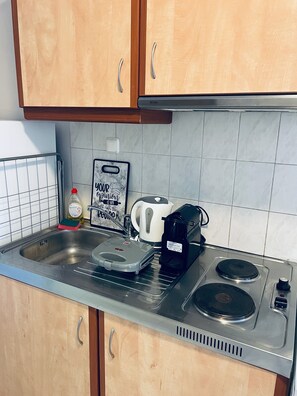 A kitchen with wooden cabinets, a stainless steel sink, a kettle, a coffee maker, and a scale. - #704: Extra Spacious Studio (28m²), Metro, Heart of Thessaloniki "Frangomahala". (Thessaloniki)