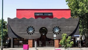 Un edificio con un diseño arquitectónico único que presenta una gran estructura con forma de ola y dos ventanas circulares.
