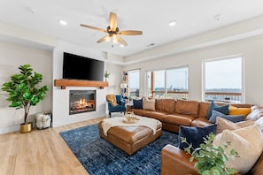 A modern living room with a fireplace, leather sofa, blue rug, and a ceiling fan. - Stunning view-Hot Tub-Game Room-Indoor Pool Access (Branson)