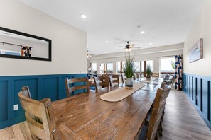 Un'ampia sala da pranzo con un lungo tavolo in legno, sedie e piante in vaso.