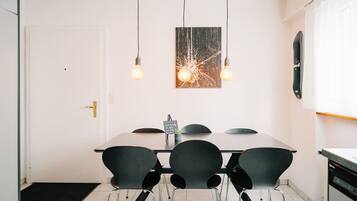 A modern dining area with a rectangular table, four black chairs, and pendant lights.