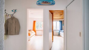 Een gang die leidt naar een slaapkamer met een bed, een bureau en een stoel.