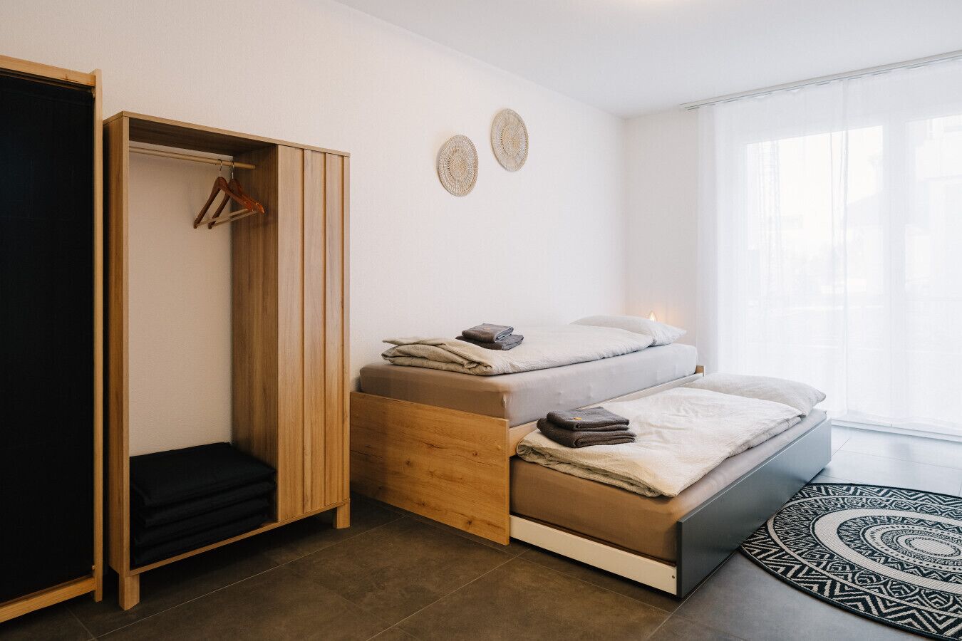 A compact bedroom with a bed, a wardrobe, and a small seating area.