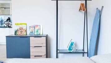 Ein modernes Schlafzimmer mit einem Bett, einem Schminktisch, einem Kleiderschrank und einer Kleiderstange mit Kleidung und einem Handtuch.