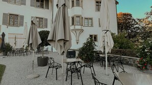 A courtyard with outdoor seating, a white building with a tower, and a clear sky. - Apartment Eiger with lake and mountain view (Spiez)