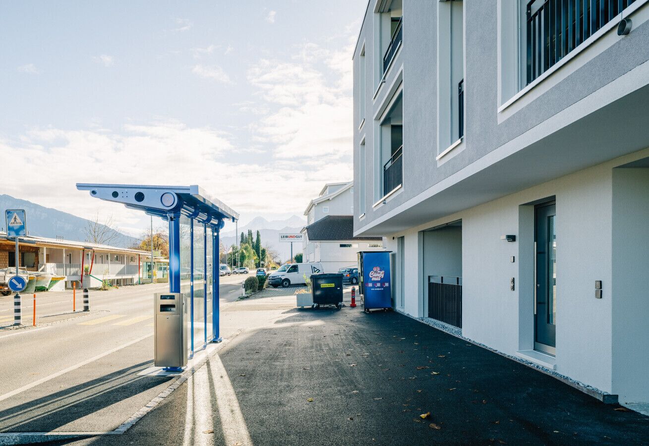 A modern building with a covered walkway, a parking area, and a visible sign for a business named "Leimbuchgut".