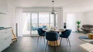 Un comedor moderno con una mesa redonda, cuatro sillas y una lámpara colgante.
