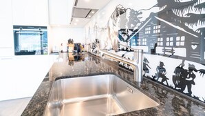 Una cocina moderna con un lavamanos de acero inoxidable, encimeras de granito y un mural que representa una escena de montaña nevada.