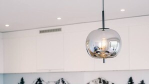 Cocina moderna con armarios blancos, una mesa de comedor para cuatro personas y un salpicadero decorado con motivos de montaña.