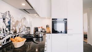 Una cocina moderna con armarios blancos, un refrigerador de acero inoxidable y un horno negro.