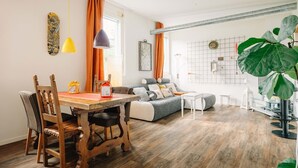 A modern living room with a wooden dining table, a sofa, and a large plant. - Loftwohnung in Seenähe (Spiez)