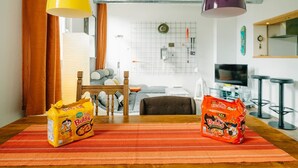 A modern living room with a wooden dining table, two hanging pendant lights, a sofa, and a TV. - Loftwohnung in Seenähe (Spiez)