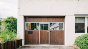 A modern building with a large wooden door, a small window, and a number plate '31a' on the door. - Loftwohnung in Seenähe (Spiez)