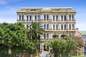 En stor, historisk bygning med en symmetrisk facade, mange vinduer og en central indgang med trapper.