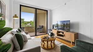 Un salon moderne avec un canapé, une table basse en bois et un téléviseur posé sur un meuble en bois.