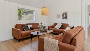 Un salon avec deux canapés marron, une table basse et un luminaire suspendu.