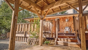 A wooden gazebo with a stone wall and steps leading to a porch with Adirondack chairs. - Tonquin Beach House - Wood Fireplace | EV Charger | Steps from Beach I Tofino (Tofino)