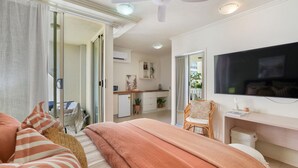 A bedroom with a bed, a TV, a desk, and a chair. There is a sliding door leading to a balcony. - Luxurious City Centre Studio - Space & Style (Cairns City)