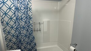 A bathroom with a white bathtub, a white sink, and a shower curtain with a blue geometric pattern.