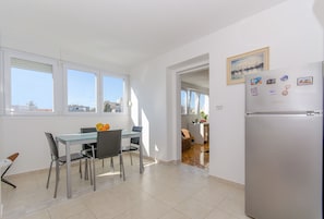 A modern kitchen with a dining area, large windows, and a refrigerator with magnets. - Apartment Neven with two ac units, close to the very center (Split)